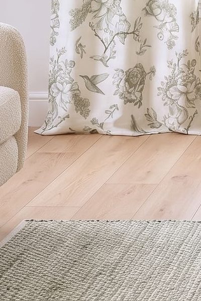 A sage and ivory accent rug by a cream sofa